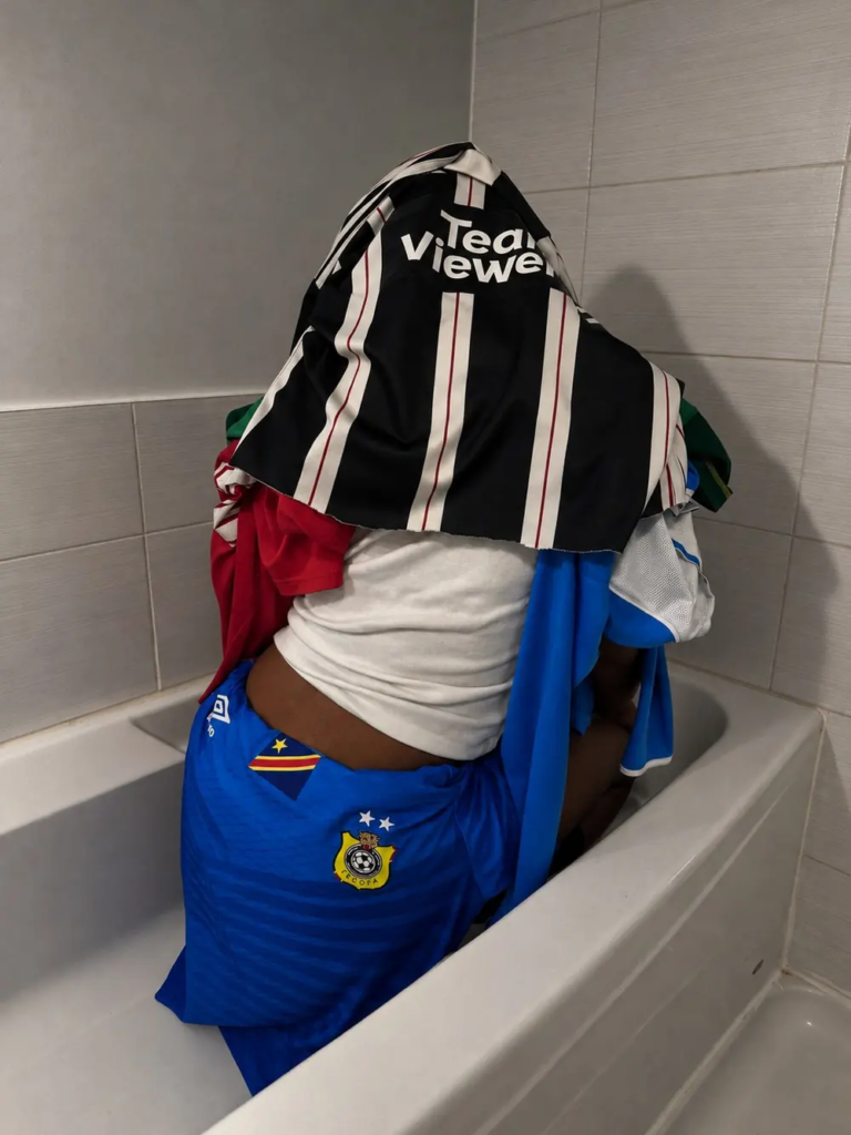 Jersey Studies — model covered in layered football jerseys, casting archive frame 33